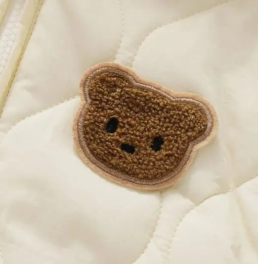 Brown bear-shaped patch on a beige quilted surface